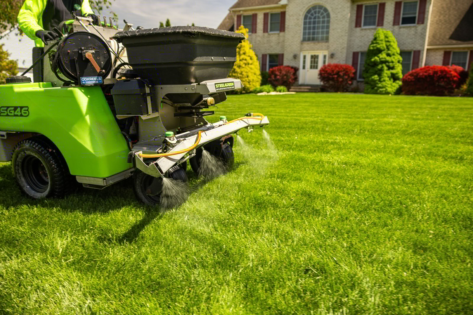 lawn care technician operating a lawn sprayer for weed control in front of a nice house 9
